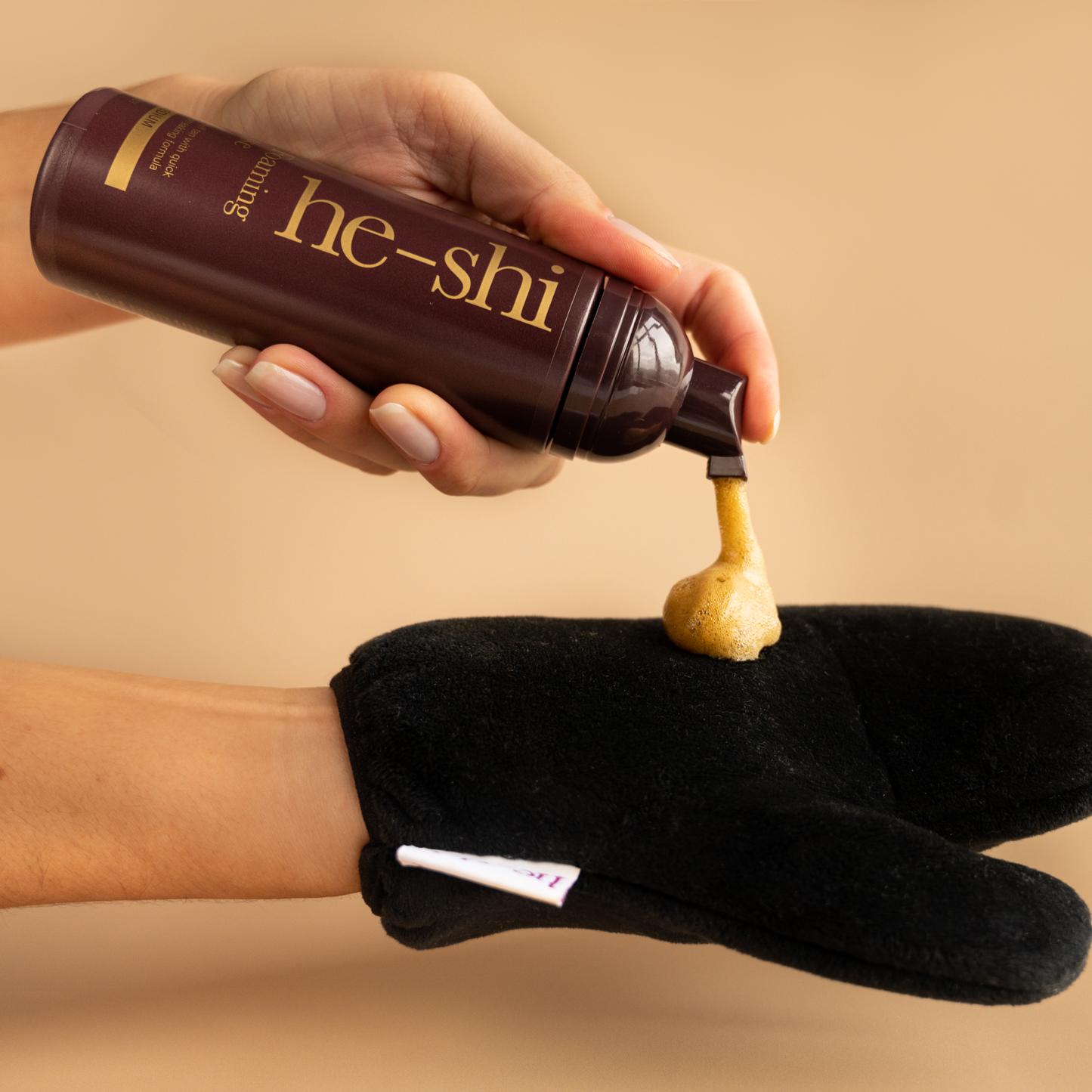 Image of hand pumping He-Shi Gold Foaming Mousse onto a tanning mitt