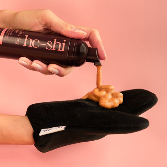 he-shi dark foaming mousse foam being pumped onto a black velvet tanning mitt