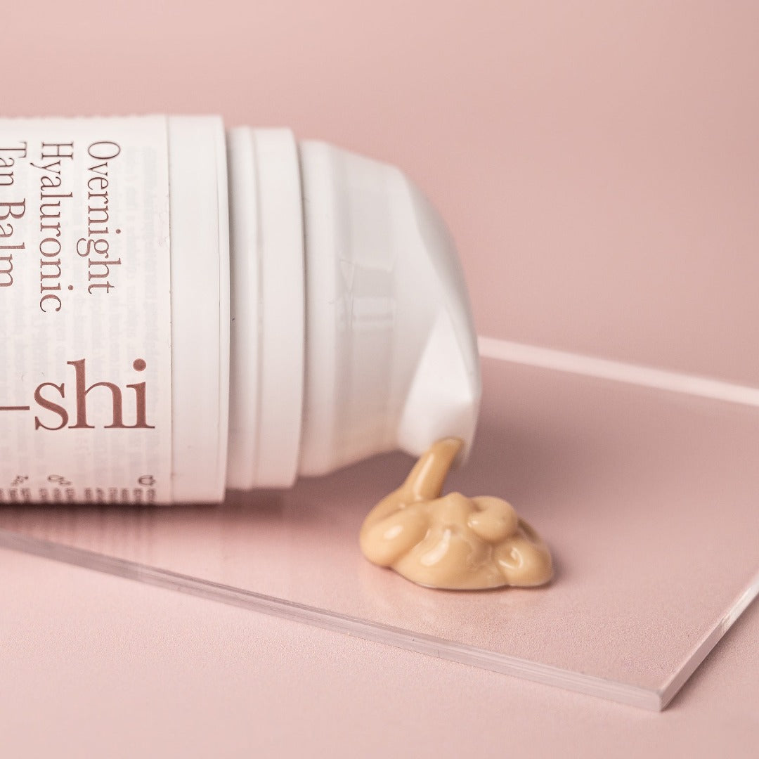 Overnight tanning cream texture shown coming out of a white airless container onto a glass plaque